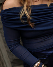 Navy blue off-shoulder top worn by a person with blurred background