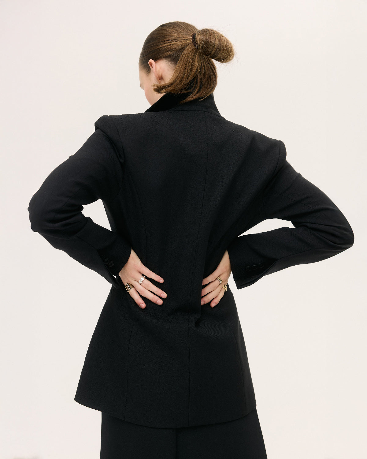 Person wearing a black suit with a plain background