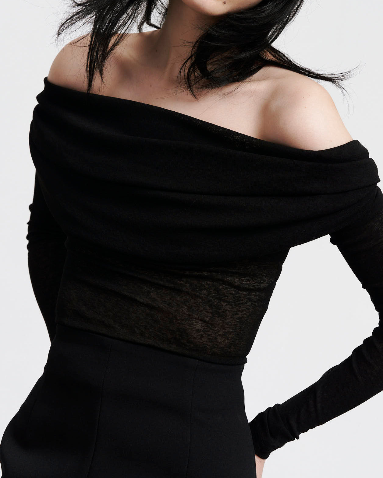 tight detailed mage of The Ada Top, a Black semi sheer, rouched off the shoulder top on women with dark hair and hands gently placed behind her back 