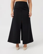 Woman with a curvaceous figure wearing a high-waisted maxi length black skirt with middle split.