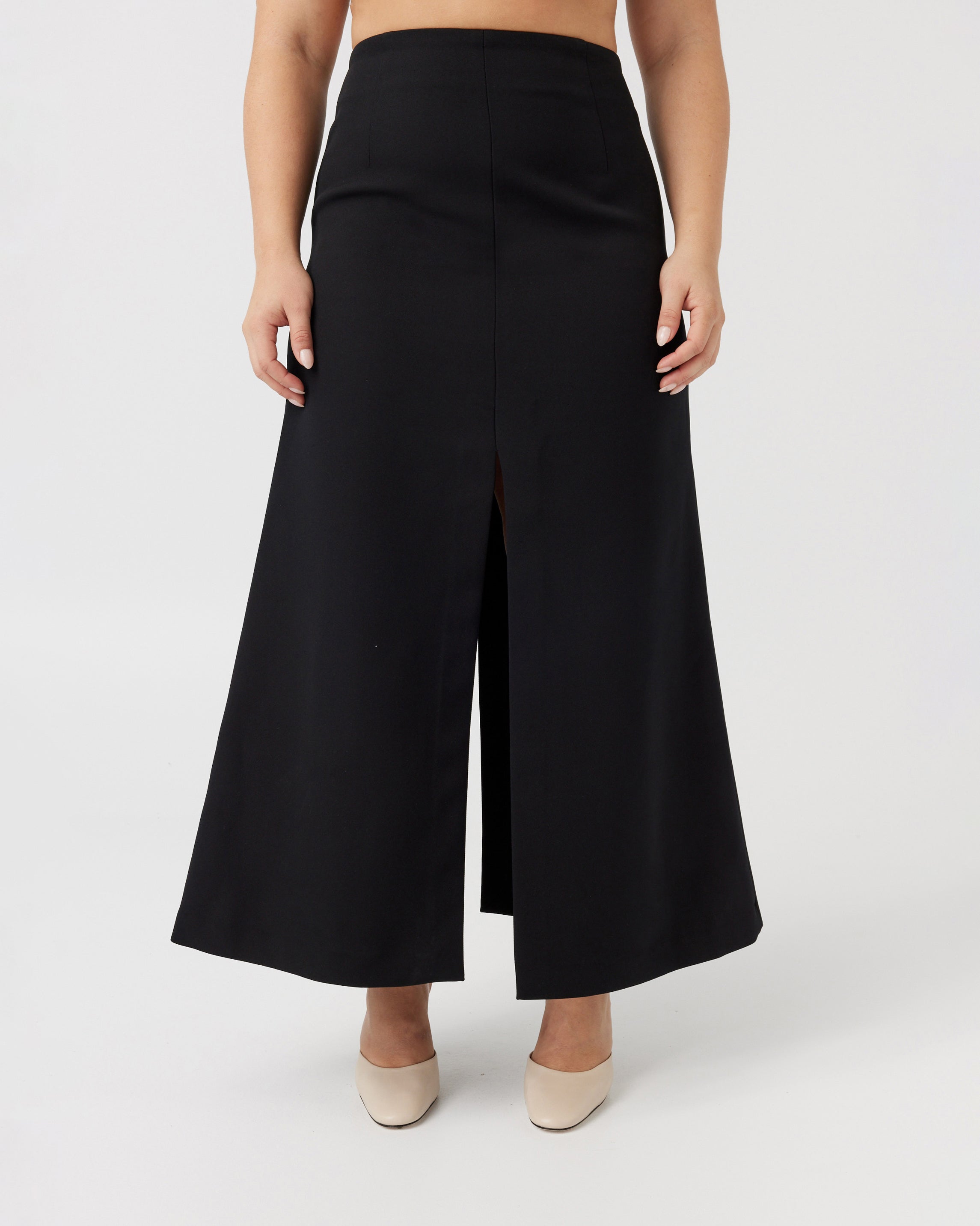Woman with a curvaceous figure wearing a high-waisted maxi length black skirt with middle split.