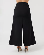 Woman with a curvaceous figure wearing a high-waisted maxi length black skirt with middle split.