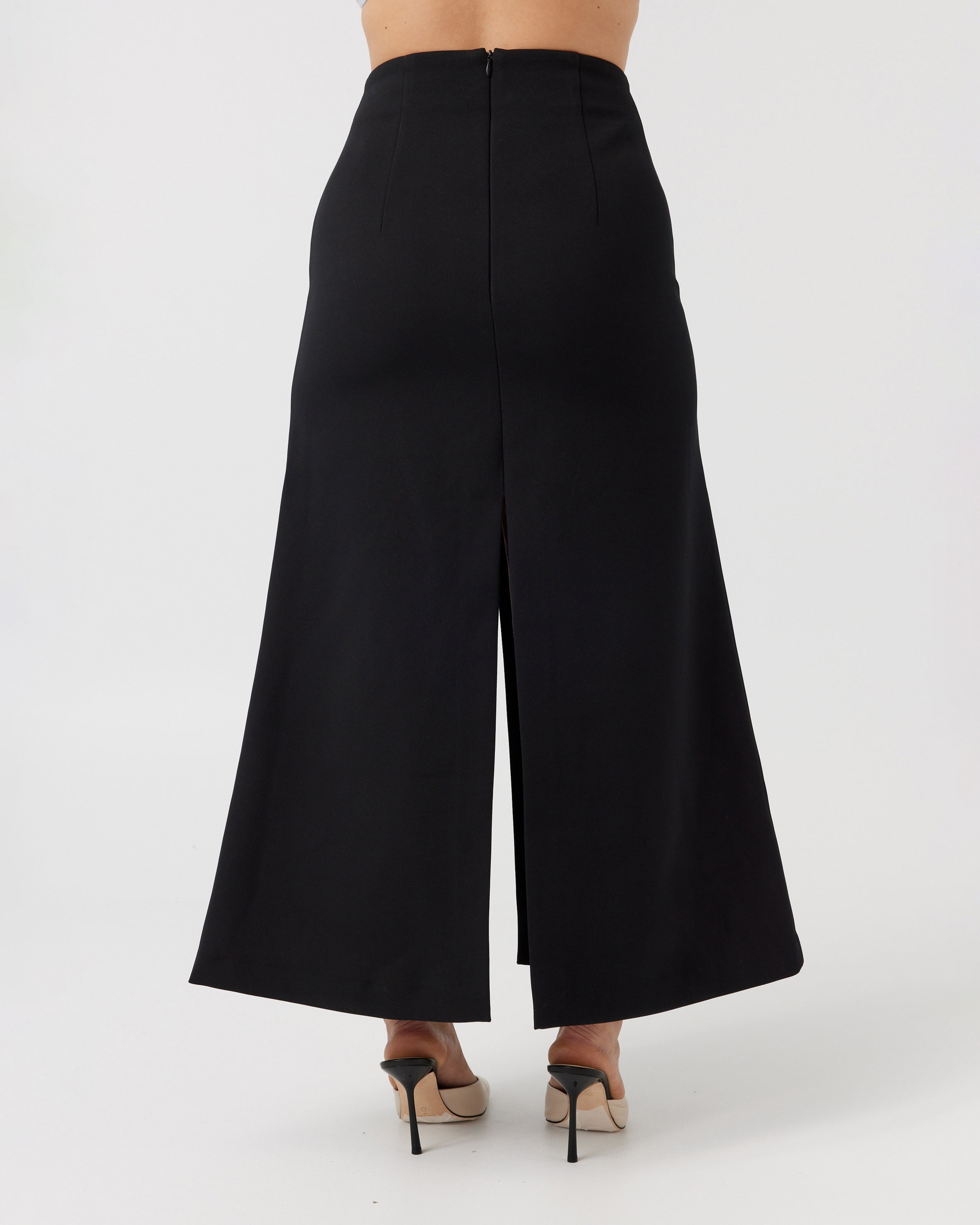 Woman with a curvaceous figure wearing a high-waisted maxi length black skirt with middle split.